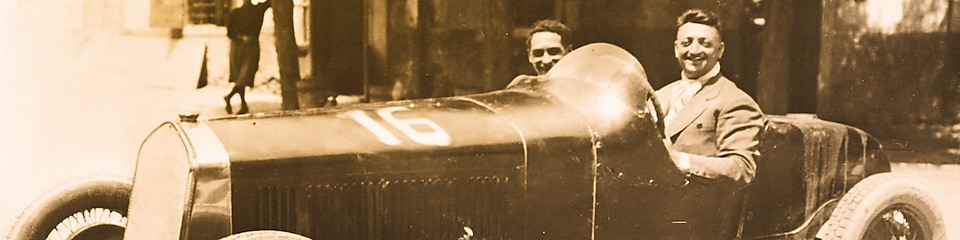 Photo en noir et blanc d'Enzo Ferrari assis dans l'une des premières Ferrari